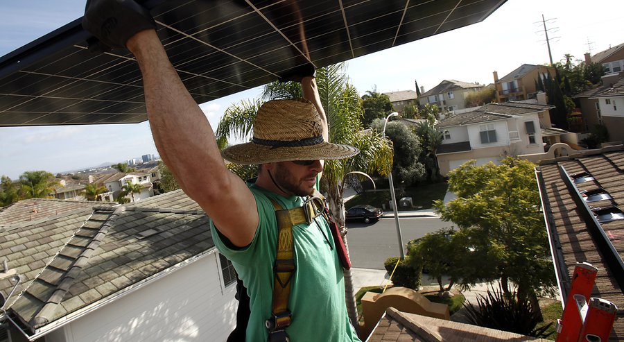 David Miller of SolarCity carries a photovoltaic panel ready to be installed on a home in Torrey Hills. 